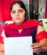 Manjit Kaur, wife of Ranjit Singh who ended his life after being implicated in a graft case, shows a copy of the court order at her residence in Mohali on Thursday. Tribune photo: Parvesh Chauhan
