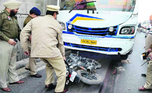 Policemen take out the bike from under the bus near Khalsa College in Jalandhar on Thursday.