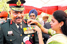 A student pins flag on the uniform of Maj Gen Binoy Poonen