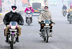 Motorcyclists cover their faces to protect themselves from the cold while venturing out in Bathinda on a chilly winter morning