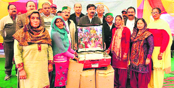 Industry Minister Mukesh Agnihotri distributes solar cookers to beneficiaries of the Swan river IWMP at Khad village in Una on Saturday.