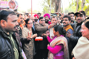 BJP workers offer sweets to chief of the state party unit Teerath Singh Rawat in Dehradun on Sunday to celebrate the BJP victory in four states . 