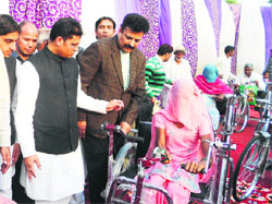 MP Ashok Tanwar gives away a wheelchair to a differently abled woman at Sirsa on Sunday. 