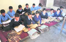 Students of Government Boys Primary School, Chakroi, sit on mats on a cold winter day as the school has no infrastructure