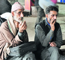 Despite ban, men smoke cigarettes at the bus stand in Jammu.