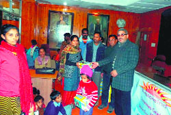 MC president Manmohan Singh Mall distributes shoes to school children in Mussoorie on Tuesday.