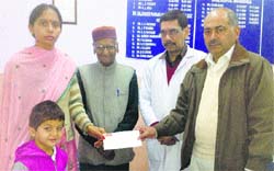 Dr Raman Puri, officiating SMO, Zonal Hospital, Dharamsala, hands over a cheque for ~5.35 lakh to Shristri's mother. Photo: Ashok Raina 