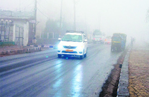 Vehicles slowly make their way through fog near the Dal Lake in Srinagar on Thursday. 