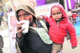 Seeking warmth: A woman with a baby in her lap sips a cup of tea to beat the cold in Bathinda on Saturday