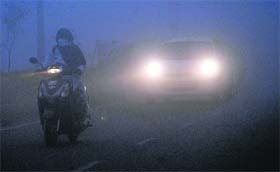With the head lights on, vehicles move at a snails pace on a road in Amritsar on Monday