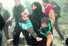 A Syrian woman carries children following airstrikes on a rebel area of the war-torn northern city of Aleppo on Sunday