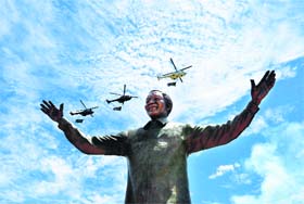 Helicopters carrying the national flag fly over a 9-metre bronze statue of South African former president Nelson Mandela which was unveiled in Pretoria on Monday