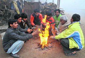As the cold wave engulfs the region, people light a bonfire for comfort in Bathinda on Tuesday.
