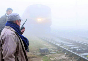 A railway official monitors the passage of trains on a foggy day at Amritsar railway station on Tuesday.