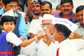 Schoolchildren offer coconut water to social activist Anna Hazare to break his fast at Ralegan Siddhi in Maharashtra on Wednesday