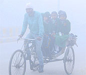Heavy rush at the busy Bbandari bridge; and (right) schoolchildren commute on a rickshaw as fog envelops the city during the morning hours in Amritsar on Thursday