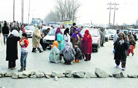 Women block a road during a protest against power cuts and increase of power tariff at Bemina in Srinagar on Thursday