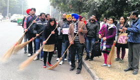 Computer teachers clean the road in a symbolic protest against the UT Education Department at the Masjid ground in Sector 20, Chandigarh, on Saturday.