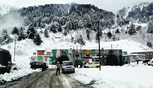 Vehicles wait at Jawahar Tunnel near Qazigund in Anantnag district on Sunday after snow and landslides.
