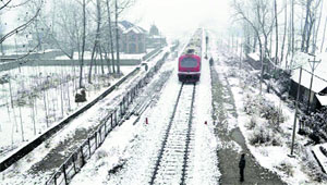 A train moves on the snow-covered Srinagar-Qazigund track on Sunday. 