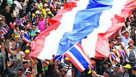 Anti-government protesters hold a giant national flag as they march through the streets of Bangkok on Sunday.