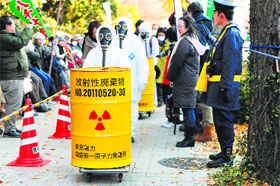 Protesters clad in protective suits carry barrels of mock nuclear waste during a rally denouncing the Japanese government direction to resume nuclear power plants, in Tokyo on Sunday.