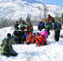 Tourists enjoy a fresh spell of snowfall near Nehru Kund on Monday.