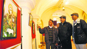 People have a look at art works during a painting exhibition at Gaiety Theatre in Shimla on Monday.