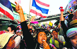 Anti-government protesters wave national flag and blow whistles as they take out a rally at Victory Monument in Bangkok on Monday.