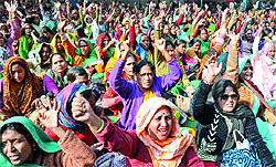 All India Anganwadi workers raise slogans during a demonstration, demanding pension and higher salaries at Jantar Mantar in New Delhi on Tuesday
