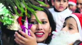 A woman holds her son, dressed up as Santa Claus, during Christmas celebrations at ABC Montessori School in Ludhiana.