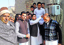 Rania MLA Krishan Kamboj removes the supply line of a house from a meter to provide it a direct connection at Keharwala in Sirsa on Wednesday