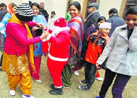A youth dressed as Santa Claus dances with women and children outside Holy Family Catholic Church during Christmas celebrations in Srinagar on Wednesday