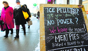 People walk past an advertising board offering hot pies to those affected by the ice storm in Toronto on Wednesday. 