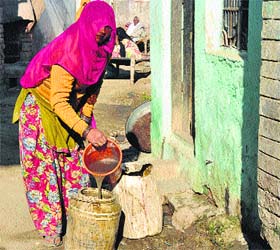 A woman collects dirty water for disposal in Bhagpati village (ward 2) of the Karnal MC
