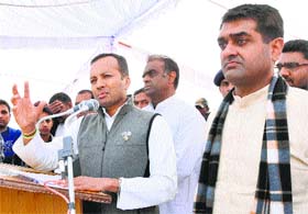 Kurukshetra MP Naveen Jindal addresses the audience as Brijender Mann (left) and Ranbeer Mann (right) look on during a rally at Mor Majra in Karnal on Sunday