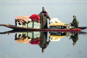 Kashmiris transport their belongings to a safer place after their houses were destroyed in the fire