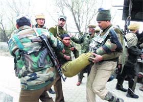 Paramilitary soldiers carry their injured colleague near an encounter site in the Bemina area of Srinagar on March 13
