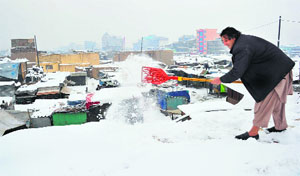 A man shovels snow from the rooftop of his shop in Kabul on Monday. About two inches of snow fell overnight in Kabul marking the winter seasons first snowfall in the city.