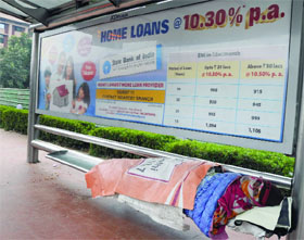 A man shields himself from the biting cold at an isolated bus stand near Air Force Headquarters in New Delhi on Tuesday.
