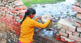 A girl throws sewage into a field in Bhagpati village of Karnal.