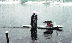 A man ferries people in a boat amid snowfall in Srinagar on Tuesday. Photo: Yawar Kabli