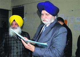 Mayor Harcharan Singh Gohalwaria checks the attendance register of employees working at the MC Zone B office in Ludhiana on Tuesday