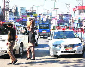 A car with red beacon atop moves in a wrong direction while a policeman looks the other way at Clock Tower in Dehradun on Friday.