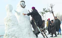 A Kashmiri youth making a snowman near the Dal Lake in Srinagar on Friday. Tribune Photo: Mohd Amin War