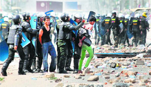  Cambodian policemen arrest garment workers in Phnom Penh on Friday. Three people were left dead and several injured as the police opened fire on protesters demanding higher wages.