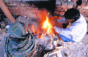 People sit by a bonfire to keep themselves warm on a chilly day in Amritsar on Sunday.