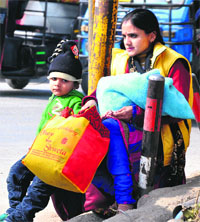 A woman, along with her kid, faces inconvenience owing to a strike by small passenger vehicle owners in Dehradun on Sunday. 
