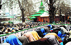 Devotees offer prayers at the shrine of Khwaja Naqshband Sahib amid snowfall at Srinagar on Sunday