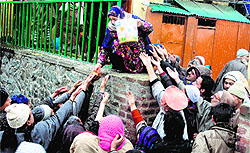 A woman distributes food among devotees after performing prayers at the shrine of Sufi Saint Khawaja Naqshband on his death anniversary in Srinagar on Sunday